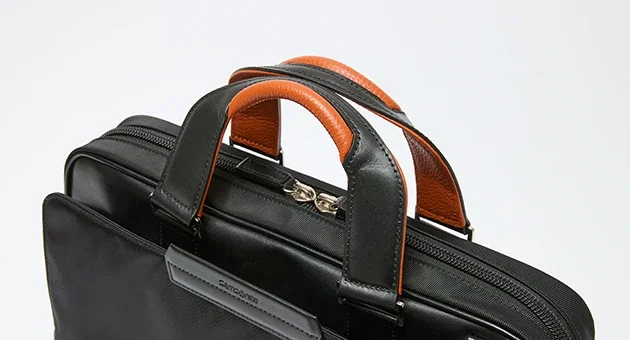 Samsonite（サムソナイト）ビジネス用ブリーフケース、バックパックであるEPID4のハンドル部分の寄り画像。上質なイタリア製レザーを用いたハンドル。オレンジカラーがアクセント。